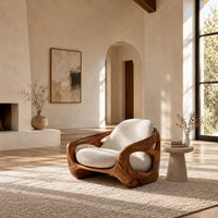 Sculpted lounge chair with oval side cutouts and cream seat cushions in a bright open plan living room
