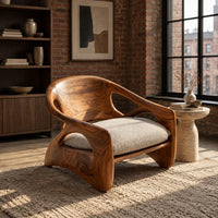 Sculpted wood chair with oval back cutouts and a cushioned seat in an industrial loft living room with exposed brick