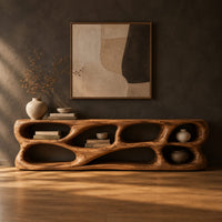 Free form tv stand made of thick sculpted wood with many oval openings in a dark studio against a charcoal plaster wall