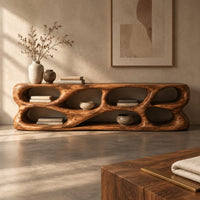 Corner detail of free form tv stand made of thick sculpted wood with many oval openings beside wood, brass and linen samples