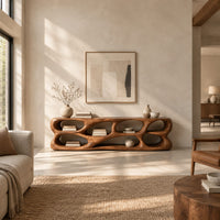 Free form tv stand made of thick sculpted wood with many oval openings in a bright open plan living room