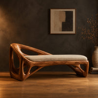 Bench with a sculpted open frame, a cushioned seat and a raised end in a dark studio against a charcoal plaster wall