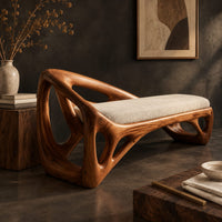 Corner detail of bench with a sculpted open frame, a cushioned seat and a raised end beside wood, brass and linen samples
