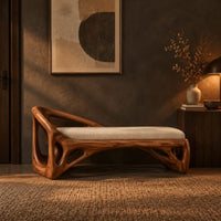 Bench with a sculpted open frame, a cushioned seat and a raised end in a dark entryway at golden hour