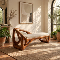 Bench with a sculpted open frame, a cushioned seat and a raised end in a bright entryway with arched windows and plants
