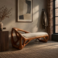Bench with a sculpted open frame, a cushioned seat and a raised end in an industrial loft entryway with exposed brick