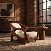 Sculpted lounge chair with an open oval wooden frame and cream cushions in an industrial loft living room with exposed brick