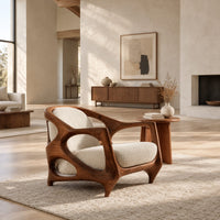 Sculpted lounge chair with an open oval wooden frame and cream cushions in a bright open plan living room