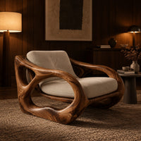 Sculpted wooden armchair with open oval side loops and cream cushions in an evening living room with walnut wall paneling