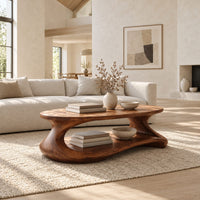 Coffee table with a sculpted pebble base and low shelf in a bright open plan living room