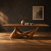 Dining table with a slab top on a sculpted pedestal with open cutouts in a dark studio against a charcoal plaster wall
