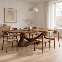 Dining table with a slab top on a sculpted pedestal with open cutouts in a Scandinavian dining room with white walls