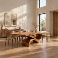 Dining table with a long plank top and one sweeping ribbon base in a bright open plan dining room