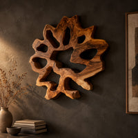 Ring shaped wall art with irregular openings and a wavy outer edge on a dark charcoal plaster wall