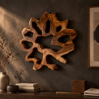 Detail of ring shaped wall art with irregular openings and a wavy outer edge beside wood, brass and linen samples