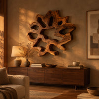 Ring shaped wall art with irregular openings and a wavy outer edge above a low console in an evening living room