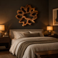 Ring shaped wall art with irregular openings and a wavy outer edge above a bed in a dusk lit bedroom