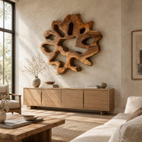 Ring shaped wall art with irregular openings and a wavy outer edge above a light oak sideboard in daylight