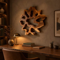 Ring shaped wall art with irregular openings and a wavy outer edge above a desk in a dark study corner