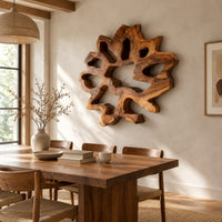 Ring shaped wall art with irregular openings and a wavy outer edge beside a dining table in natural light