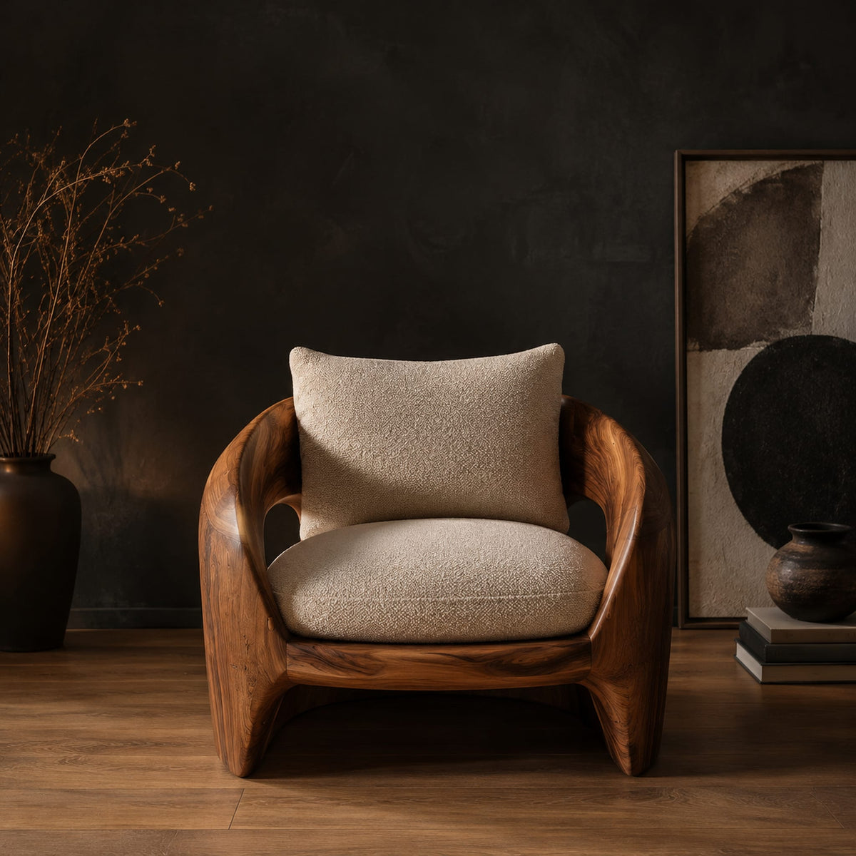 Sculpted wooden shell chair with an oval side opening and cream cushions in a dark studio against a charcoal plaster wall