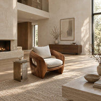 Sculpted wooden shell chair with an oval side opening and cream cushions in a bright open plan living room