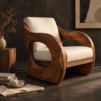 Corner detail of lounge chair with a thick sculpted wood shell and oval side openings beside wood, brass and linen samples