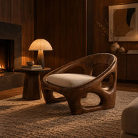 Low wood lounge chair with oval cutouts and a cream seat cushion in an evening living room with walnut wall paneling