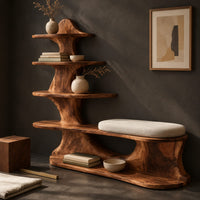 Corner detail of sculpted wood shoe bench with a cushioned seat and a tower of shelves beside wood, brass and linen samples