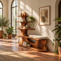 Sculpted wood shoe bench with a cushioned seat and a tower of shelves in a bright entryway with arched windows and plants