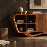 Corner detail of sculpted sideboard with open cubbies and a flowing wave base beside wood, brass and linen samples