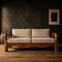 Sculpted wood sofa with open loop arms and a wavy lower rail in a dark studio against a charcoal plaster wall