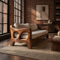 Sculpted wood sofa with open loop arms and a wavy lower rail in an industrial loft living room with exposed brick