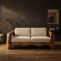 Sofa with thick sculpted arms that have oval openings and a wavy base edge in a dark studio against a charcoal plaster wall