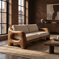Sofa with thick sculpted arms that have oval openings and a wavy base edge in an industrial loft living room with exposed brick