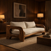 Solid wood sofa with sculpted open loop arms and a long cream seat cushion in an evening living room with walnut wall paneling