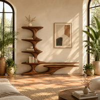 Sculpted tv stand with a stacked shelf tower and a long low ledge in a bright living room with arched windows and plants