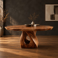 Dining table with a twisted pedestal base and a softly waved edge top in a dark studio against a charcoal plaster wall
