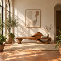 Low bench with a raised wave at one end and an open loop base in a bright entryway with arched windows and plants