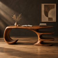 Desk with a large curled leg and stacked shelf tiers at the opposite end in a dark studio against a charcoal plaster wall