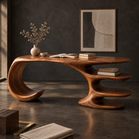 Corner detail of desk with a large curled leg and stacked shelf tiers at the opposite end beside wood, brass and linen samples