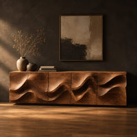 Long low sideboard with sculpted wave relief across the doors in a dark studio against a charcoal plaster wall