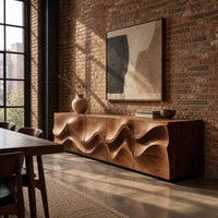 Long low sideboard with sculpted wave relief across the doors in an industrial loft dining room with exposed brick