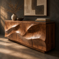 Corner detail of low sideboard with wave relief across four panels and a recessed plinth base beside wood, brass and linen samples
