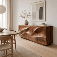 Low sideboard with wave relief across four panels and a recessed plinth base in a Scandinavian dining room with white walls