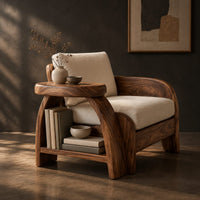 Sculpted wood chair with an oval arm ledge and a cream seat cushion, three-quarter view showing the grain