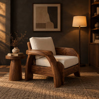 Sculpted wood chair with an oval arm ledge and a cream seat cushion in a dark living room at golden hour