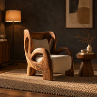 Sculpted lounge chair with looping carved arms, cutout back and cream cushions in a dark living room at golden hour