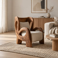 Sculpted lounge chair with looping carved arms, cutout back and cream cushions in a Scandinavian living room with white walls