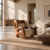 Sculpted lounge chair with looping carved arms, cutout back and cream cushions in a bright open plan living room